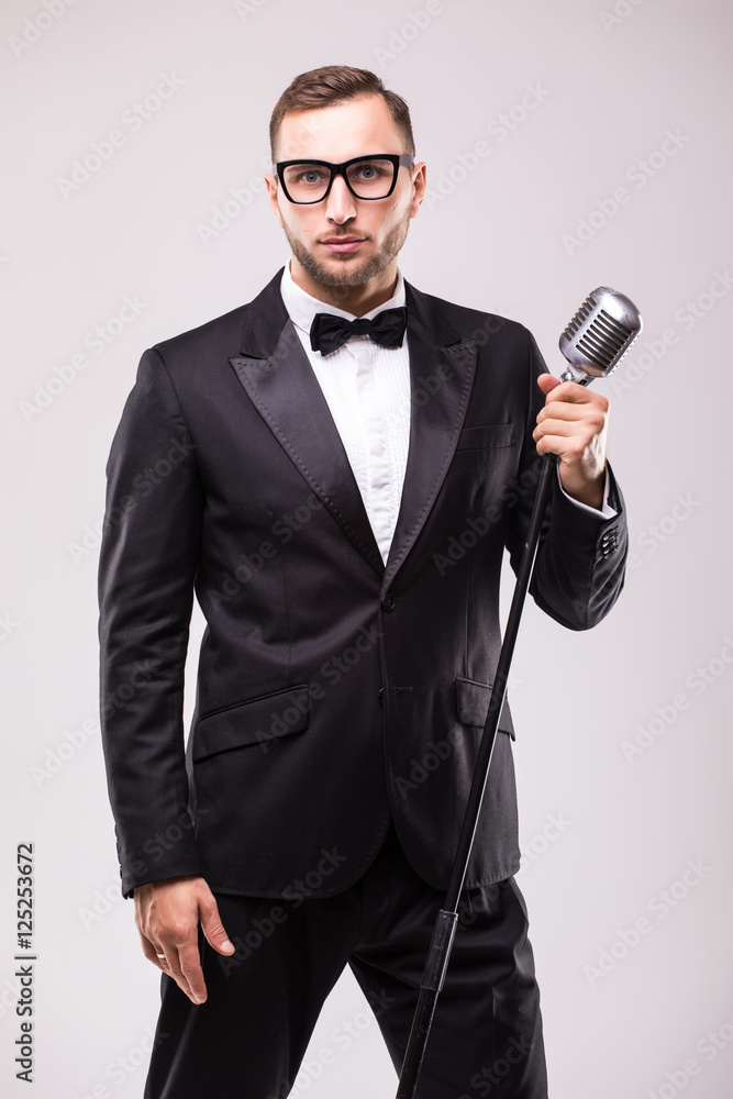 Naklejka premium Front-man in suit singing with the microphone and smile. Isolated on white background. Showman concept.