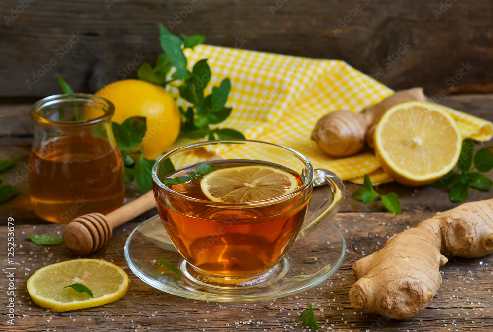 Black tea with lemon, mint and ginger on a wooden background