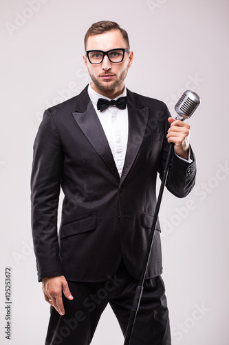 Front-man in suit singing with the microphone and smile. Isolated on white background. Showman concept.