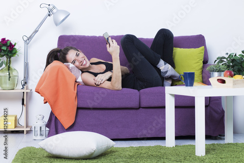 Happy young woman in the living room talking on the phone and smiling photo