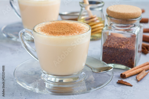 Fototapeta Naklejka Na Ścianę i Meble -  Healthy rooibos red tea latte topped with cinnamon, ingredients on background, horizontal