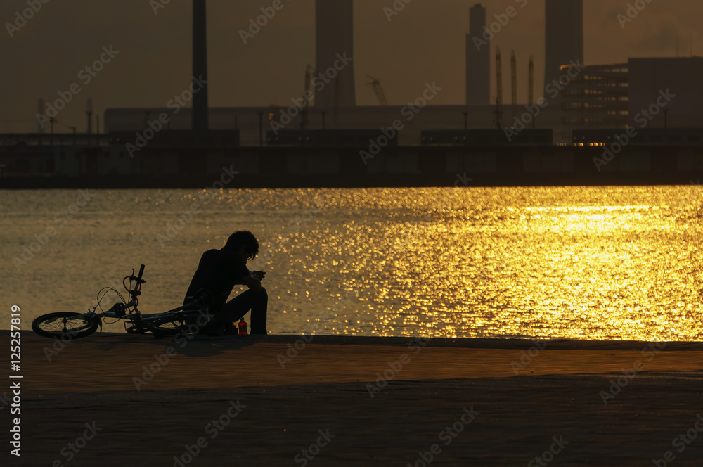 夕焼けの中 一人座る男性の後ろ姿 Stock Photo Adobe Stock