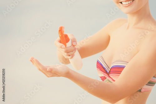 Young woman applying sunscr...