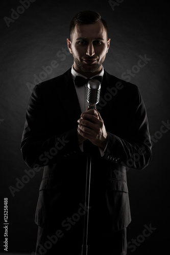 silhouette of young handsome singer on black background. Singer concept.