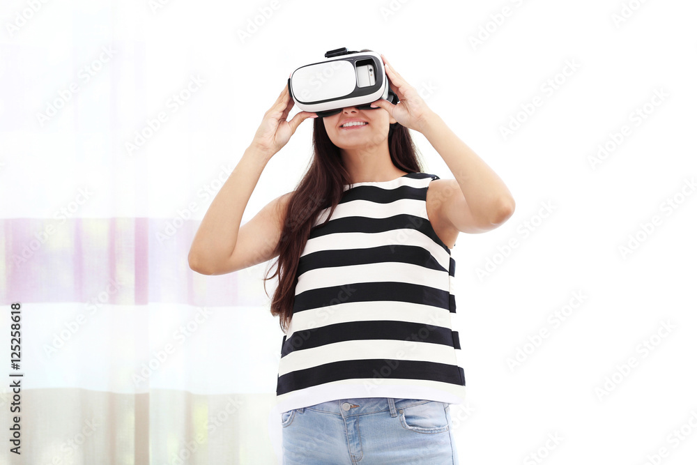 Young woman wearing virtual reality glasses and standing near window in a room Young woman wearing virtual reality glasses and standing near window in a room