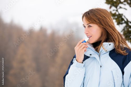 femme à la montagne s'appliquant de l'écran de protection sur les lèvres
