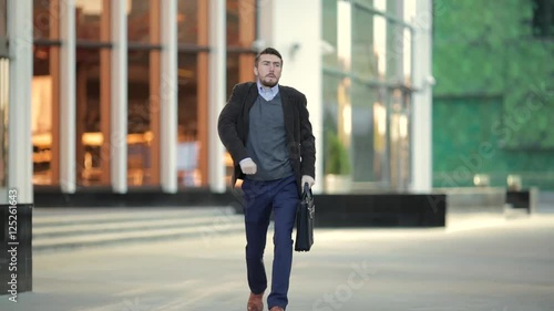 Attractive man with a beard and briefcase dancing in the street