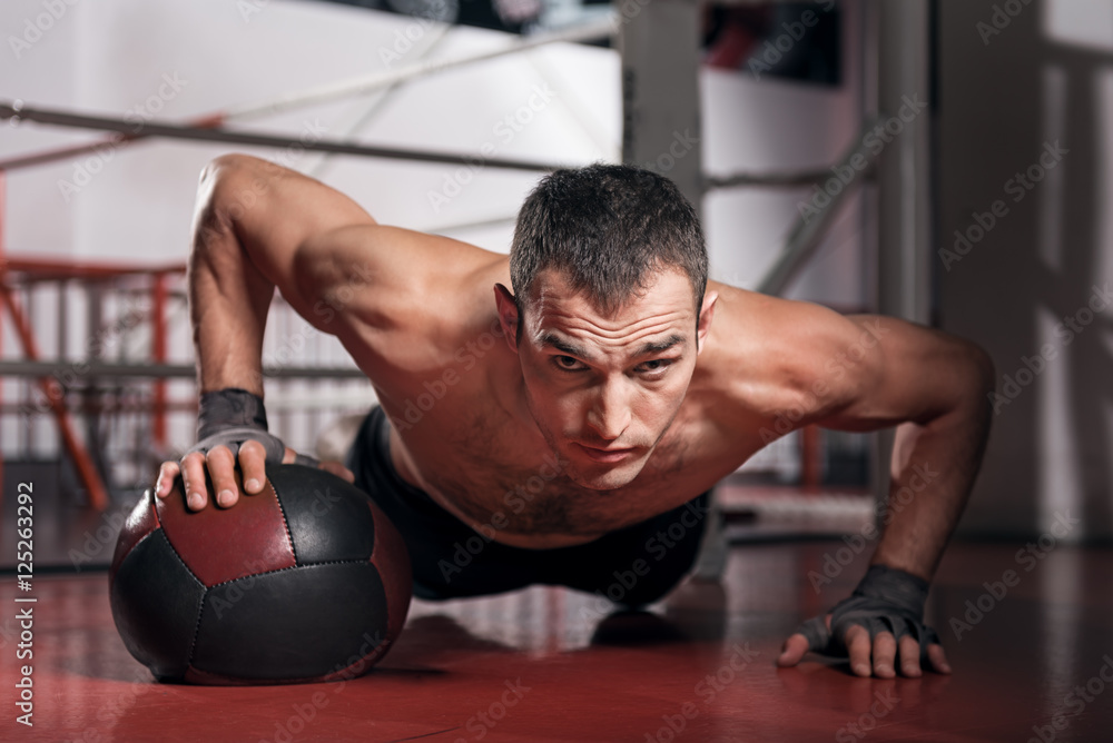 Muscular man doing push-ups with fitness ball Muscular man doing push-ups with fitness ball