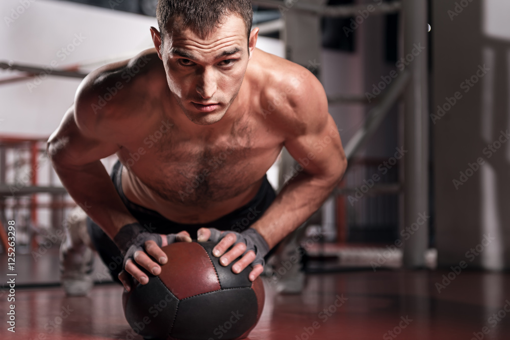 Muscular man doing push-ups with fitness ball Muscular man doing push-ups with fitness ball