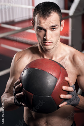 Muscular man holding fitness ball in front of chest