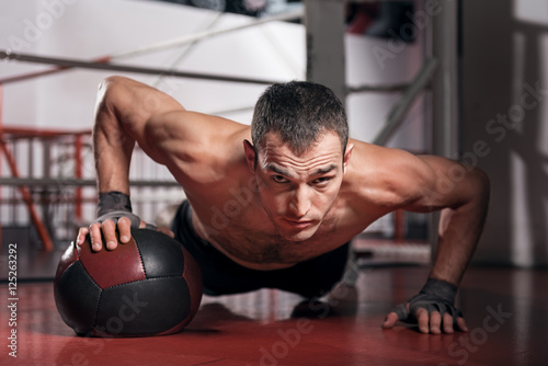 Muscular man doing push-ups with fitness ball