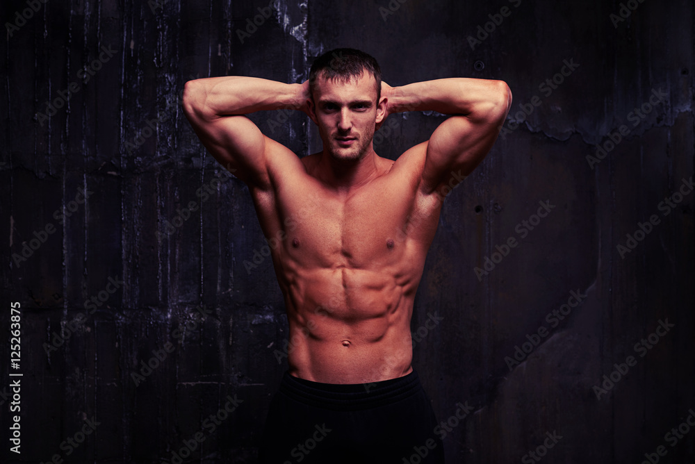 Fototapeta premium Przystojny mężczyzna z nagą klatką piersiową, doskonałym brzuchem i dobrze wytrenowaną sylwetką