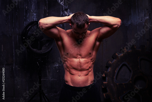 Sexy muscular man standing with hands behind his head, his abs p photo