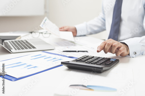 Man using calculator and holding important document