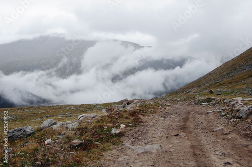 Extreme rocky stone road way in a mountain valley to the pass in cloudy weather with rain and fog Plateau Ukok Altai Siberia Russia