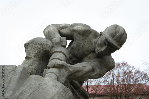 Historic statue made in socialist realism style. Realistic muscular mineworker is holding pneumatic drill. Glorification of manual work and mining and heavy industry