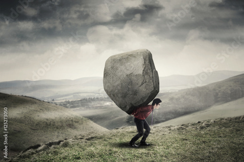 Fotografie, Obraz Businessman carrying rock at hill