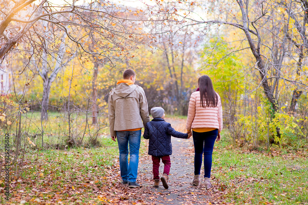 Family of three walks in the autumn park Family of three walks in the autumn park
