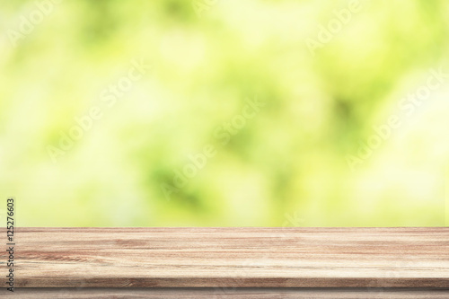 Smooth wood table with green blurry trees background, nature concept.