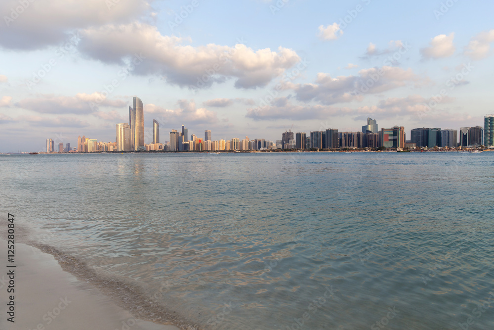 Abu Dhabi skyline with clouds and sea waves bashing