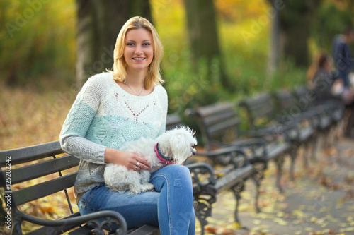Wallpaper Mural Young woman is sitting on a bench while walking her dog in a park. She is smiling and looking at camera. Torontodigital.ca