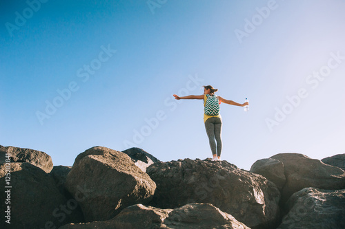 Silhouette of a young woman practicing yoga on a rocky shore