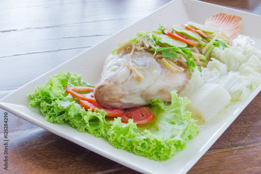 Steamed fish with chili and lemon on wood table , spicy food Steamed fish with chili and lemon on wood table , spicy food