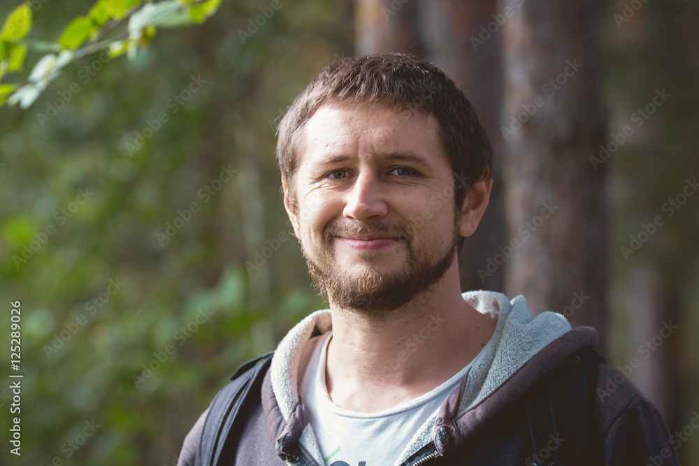Adult strong man with beard smiling in forest Adult strong man with beard smiling in forest
