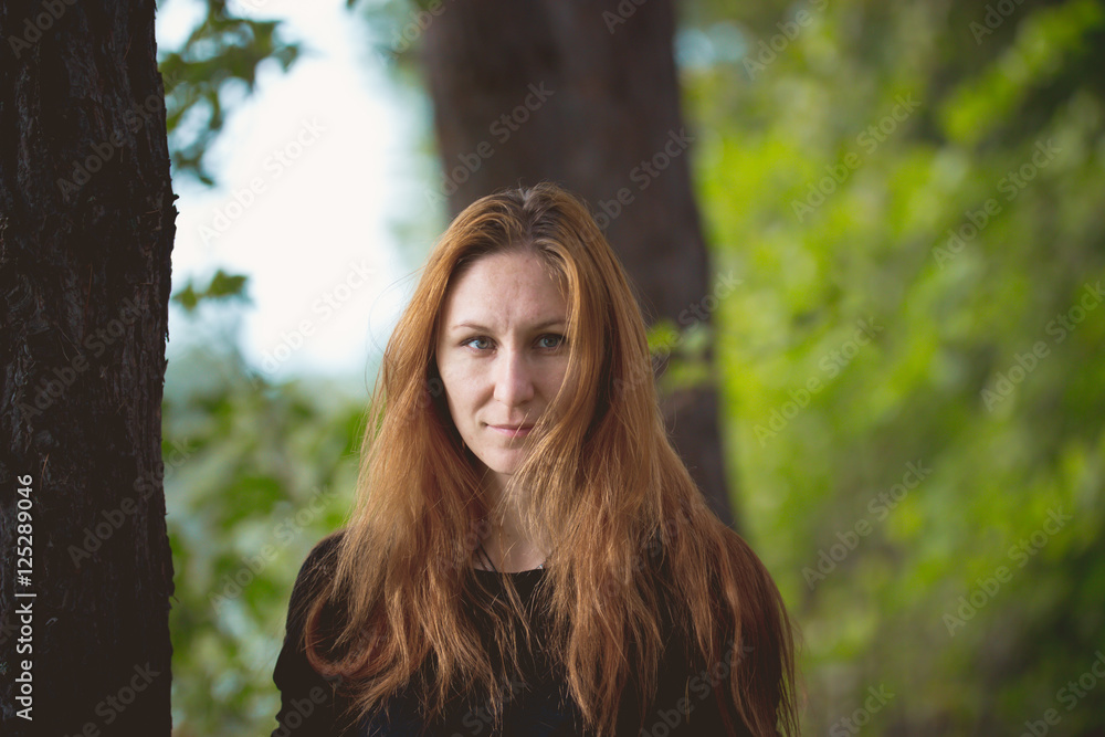 Naklejka premium Portrait of young beautiful female standing in summer forest