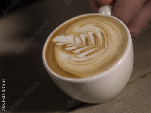 Making latte Art on a Cappucinno on a dark wooden background