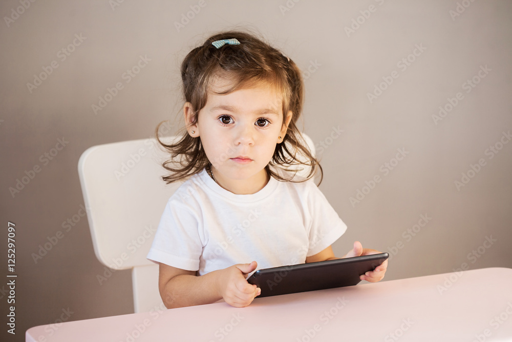 Cute little girl with tablet pc sitting at the table Cute little girl with tablet pc sitting at the table