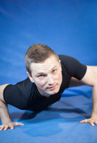 Muscular young man exercising in his fitness gym; close-up (colo