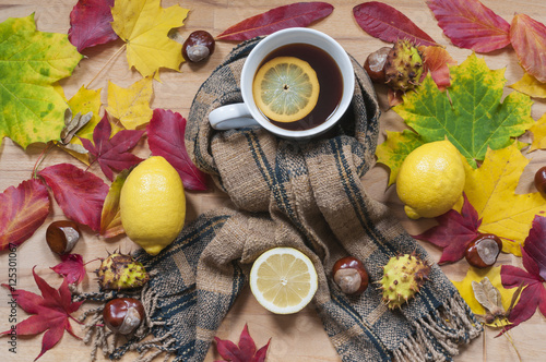 Tasse Tee mit Schal / Tasse Tee mit Zitronenscheibe, Schal und Herbstlaub mehrere Objekte in der Draufsicht fotografiert.
