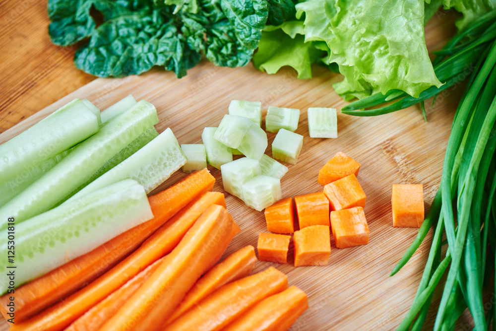 Vegetable set of sliced carrots and cucumbers, garlic, green onion and lettuce on wooden Board closeup Vegetable set of sliced carrots and cucumbers, garlic, green onion and lettuce on wooden Board closeup