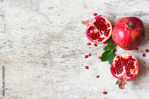 half pomegranate and ripe pomegranate fruit on white wooden rustic background