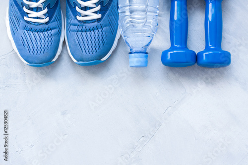 Flat lay sport shoes, bottle of water and dumbbells