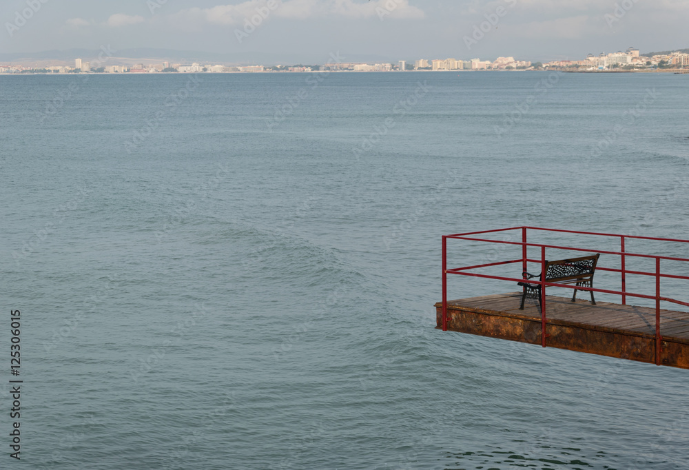 empty footbridge with a bench  over the sea