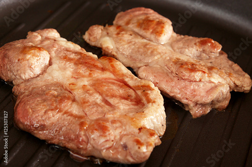 Two pieces of of grilled pork steaks over on frying grill pan