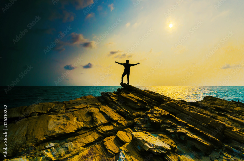 man hand up on the top stone with the sunset over sea. man hand up on the top stone with the sunset over sea.