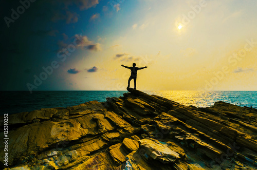Valokuvatapetti man hand up on the top stone with the sunset over sea.