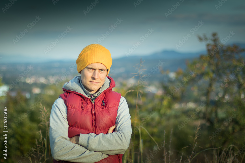 Young hipster male student in yellow hat and ren jacket outdoors Young hipster male student in yellow hat and ren jacket outdoors