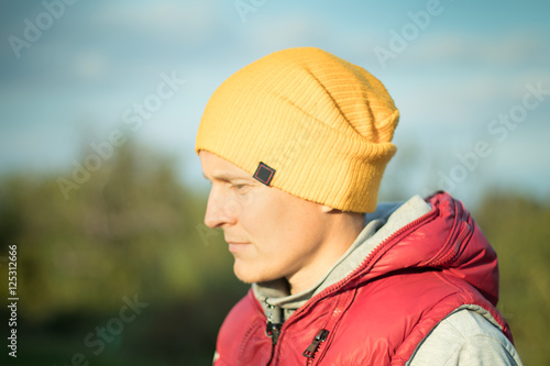 Young hipster male student in yellow hat and ren jacket outdoors