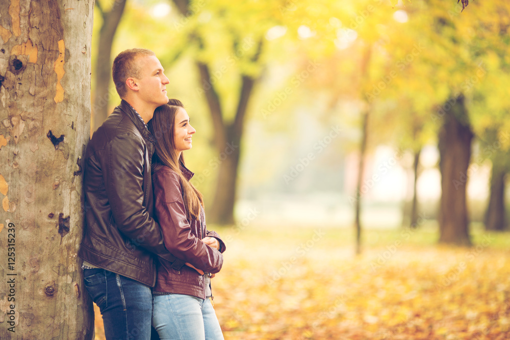 Young couple are enjoying therig time together in a park on a beautiful Autumn day.