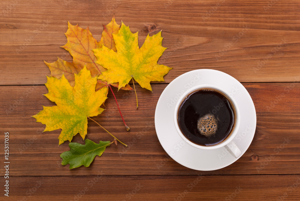 Coffee cup and autumn leaves on a wooden background. Coffee cup and autumn leaves on a wooden background.