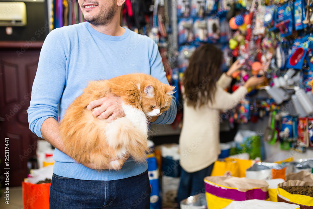 Man holding his persians cat in pet shop.