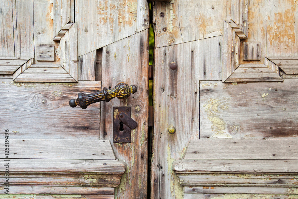 part locked old dilapidated wooden door with wrought iron lock and keyhole