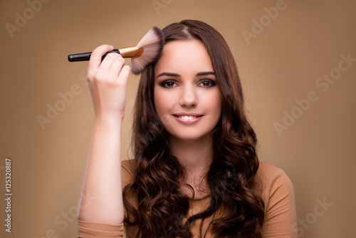 Beautiful woman applying make-up in beauty concept