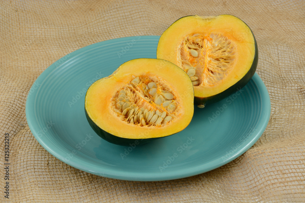 Raw uncooked acorn squash halves with seeds on blue plate Raw uncooked acorn squash halves with seeds on blue plate