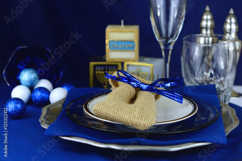 Place setting in varying shades of blue for Hanukkah. Includes shiny crystal glasses, silver salt and pepper shakers, cute holiday candles and sparkling decorations. Shallow depth of field.