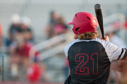 High school baseball player with long hair batting.